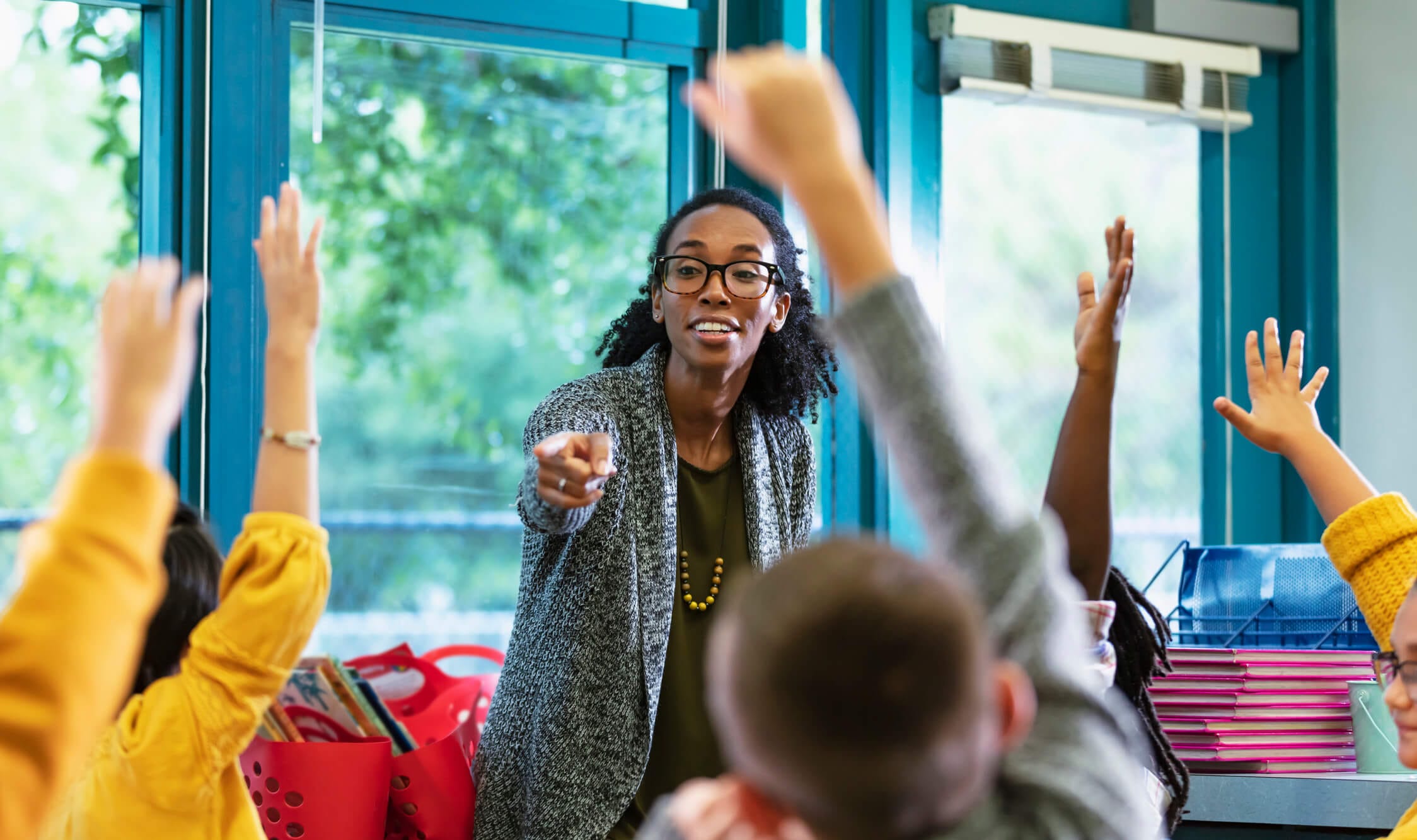 teacher calling on elementary students raising hands