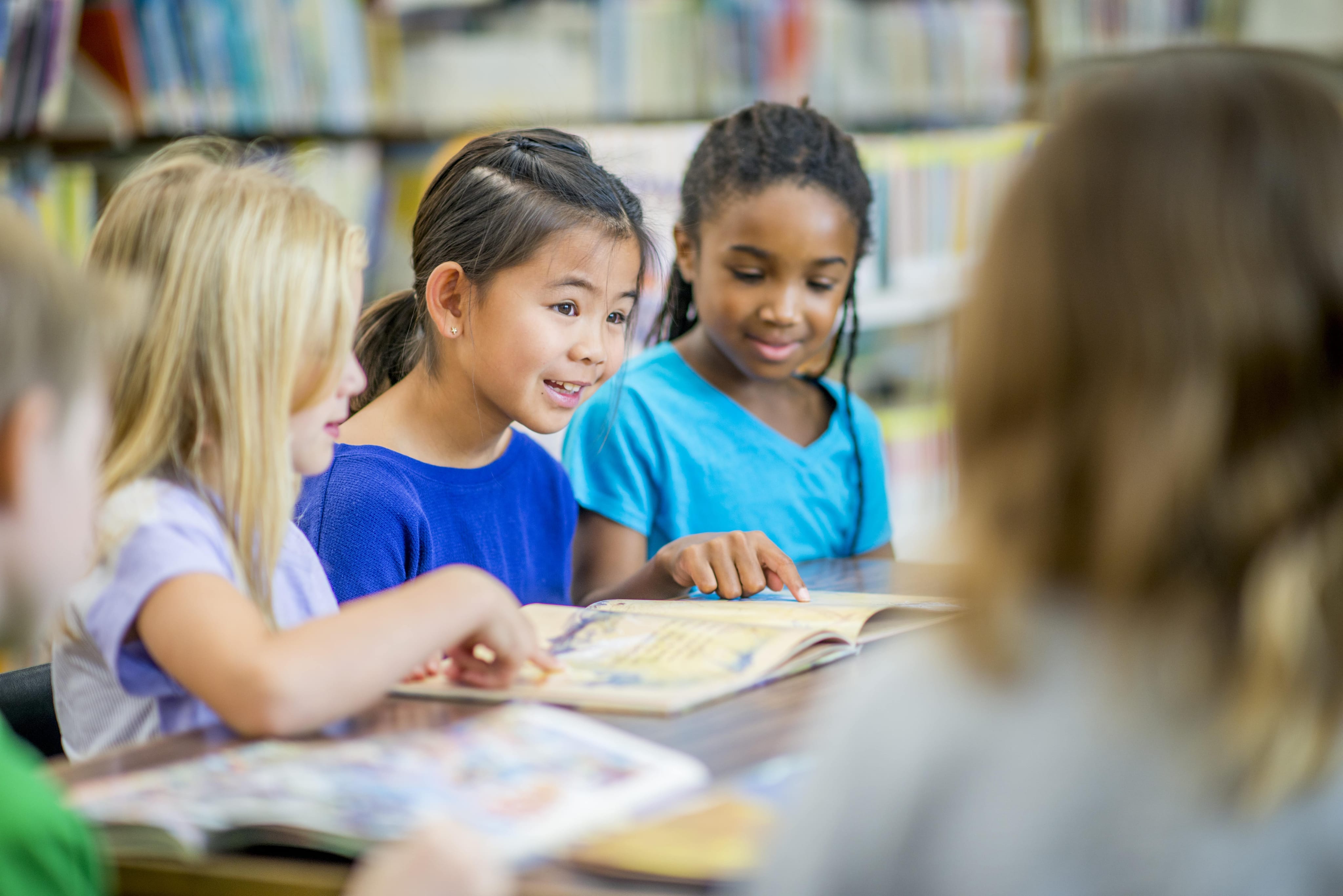 children reading a book together in library