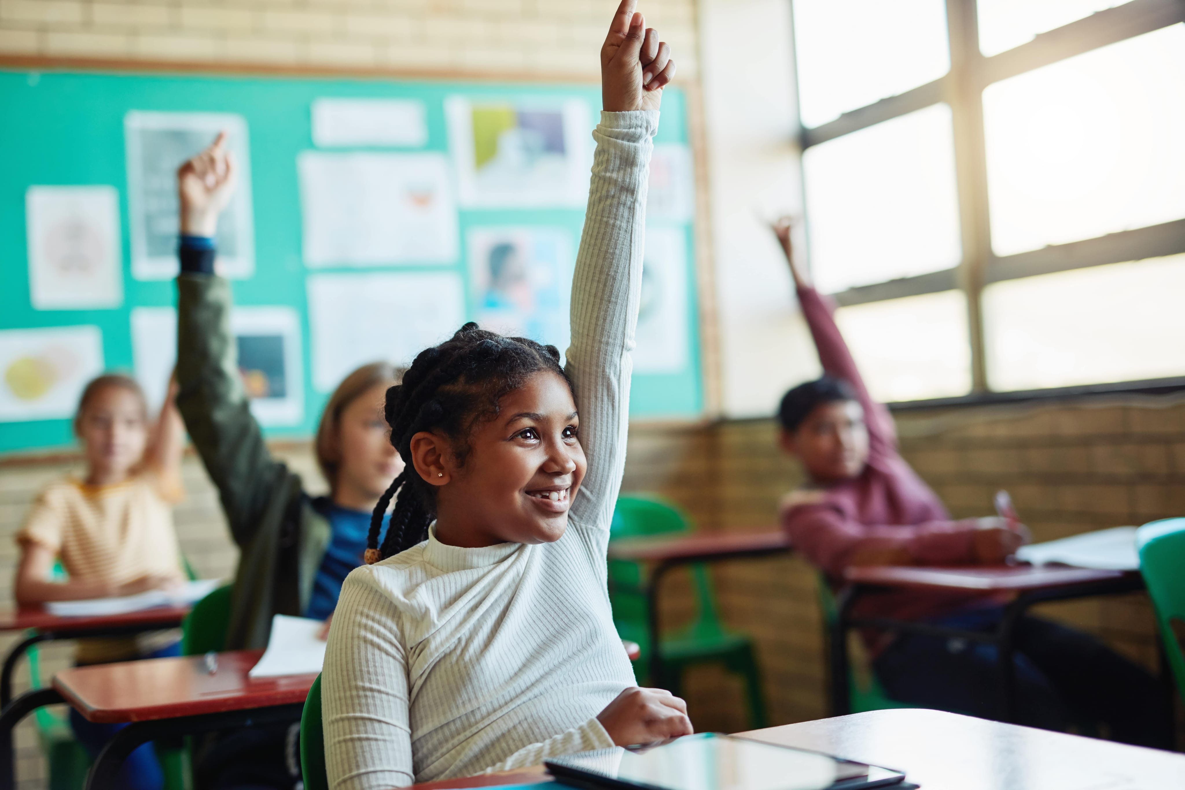 students raising hands in classroom together